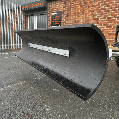 A large, curved snow plow blade made of black plastic or rubber, mounted on a metal frame with bolts. The blade is designed to clear snow from roads and other surfaces.